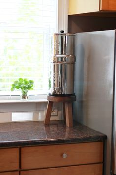 a kitchen counter top with a metal container on it's stand next to a sink