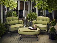 an outdoor living room with green furniture and potted plants on the decking area