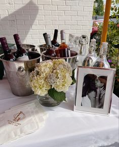 there is a vase with flowers in it on the table next to bottles and glasses