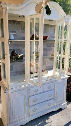 a white china cabinet with glass doors and drawers