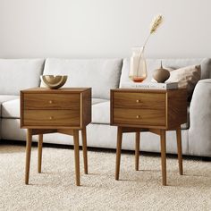 two side tables sitting next to each other on top of a carpeted living room floor