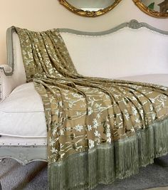 a bed with a white headboard and a gold mirror on the wall