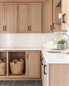 a kitchen with wooden cabinets and baskets on the counter top, along with white tiled backsplash