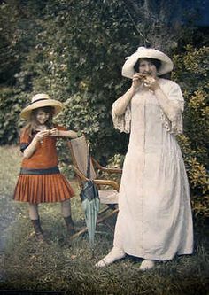 two women in dresses and hats standing next to each other