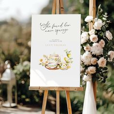 an easel with a sign and flowers on it