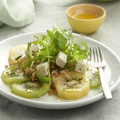 a white plate topped with sliced cucumbers and other vegetables next to a fork