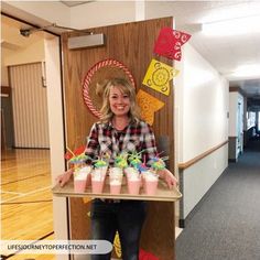 a woman holding a tray with cups on it