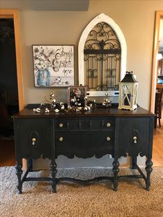 a black buffet table with gold knobs on the top and an ornate mirror above it