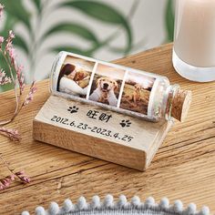 a bottle with three photos in it sitting on a wooden table next to a candle