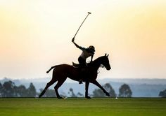 two people on horses playing polo at sunset