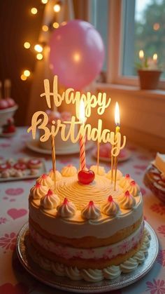 a birthday cake sitting on top of a table next to a window with lit candles