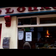 the outside of a restaurant with red balloons hanging from it's front window and signs on the wall