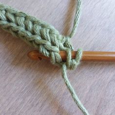 a green crochet hook on a wooden surface