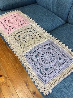 a crocheted rug is laying on a blue couch next to a wooden floor