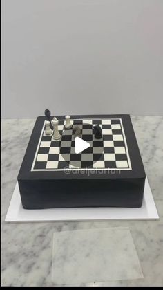 a black and white chess board cake sitting on top of a marble table with a video game in the middle