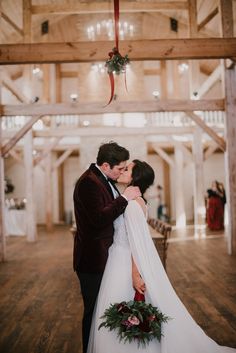 a bride and groom kissing in the middle of their wedding ceremony at an old barn