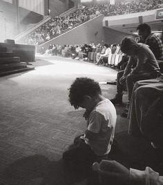 a young boy sitting on the floor in front of an audience with his head down