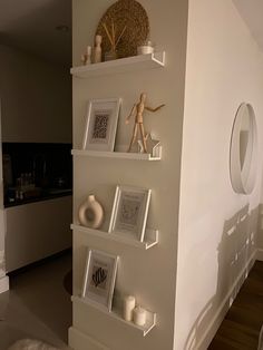 a living room filled with white furniture and pictures on the wall next to a mirror