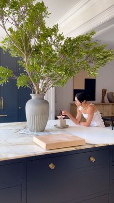 a woman sitting at a table with a potted plant in front of her on the counter