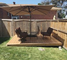 a deck with chairs and an umbrella in the middle of it, next to a fence