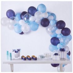 a table topped with lots of blue and white balloons