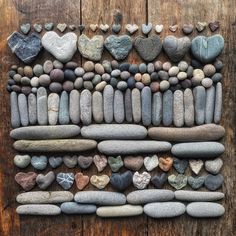 rocks arranged in the shape of hearts on a wooden surface