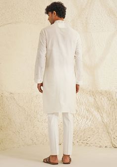 Presenting an exquisite Porcelain White Silk Kurta Set, featuring a sophisticated Chinese collar, elegant metallic silver buttons, and intricate hand-embroidered detailing on the neckline and sleeves. Paired with trendy white pants, this ensemble is perfect for engagements, Roka ceremonies, or puja events, combining timeless elegance with contemporary style. Composition : Dupion Silk Care: Dry Clean Only and Vacuum Storage This product can be customized for sleeves, length and colour Delivery : 4-6 weeks as the product is hand crafted. Check Size Guide or choose MySize for free customisation (All Sizes above XL can be made at 15% additional cost) For more information and sizes please contact fabiliciousfashion@gmail.com or visit our Copenhagen studio. About the Designer : Shreyansh, a dist Silk Kurta Set, Placement Embroidery, Kurta Set For Men, White Kurta, Chinese Collar, Indian Wedding Wear, Silk Kurta, Dupion Silk, Beaded Neckline