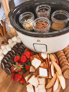 a crock pot filled with cheese, crackers and strawberries