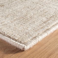 a close up view of the top of a rug on a wooden floor with a light colored finish