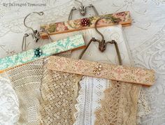 several pieces of lace hang from hooks on a white wall with lacy doily and crochet