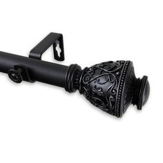 a black curtain rod with an ornate design on the top and bottom, attached to a metal hook