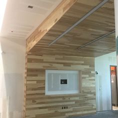 an unfinished room with wood paneling on the walls and a white square window in the center