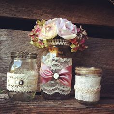 three jars with lace and flowers are sitting on a wooden bench next to mason jars