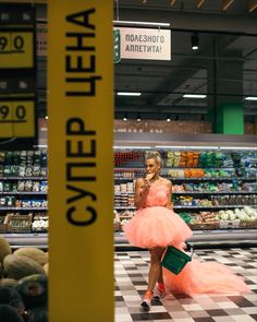 a woman in a pink dress walking through a grocery store