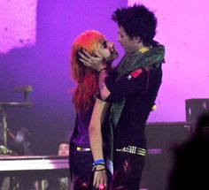 a man and woman kissing on stage at a concert