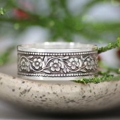 This Nature Inspired Sterling Silver Botanical Ring features a floral Daisy Chain. These bands are created with a rolling mill that embosses the pattern onto a wide strip of metal. The finished wide band measures 8 mm (approximately 0.31 inches) in width. We are happy to create this band for you in a variety of ring sizes and finishes. The intricately patterned Daisy Chain Sterling Silver band has a lovely twining Daisy Flower motif and measures 7 mm wide. The Daisy Chain band pattern continues Bohemian Stackable Wedding Jewelry, Silver Adjustable Flower Ring For Wedding, Flower Shaped Intricate Design Wedding Jewelry, Flower Shaped Intricate Wedding Jewelry, Flower Shaped Intricate Design Jewelry For Wedding, Bohemian Flower Ring For Wedding, Wedding Toe Ring With Intricate Design, Flower-shaped Jewelry With Intricate Design For Wedding, Silver Wide Band Wedding Bands