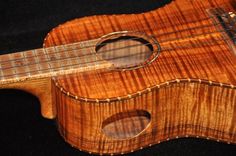 an ukulele made out of wood on a black background with the strings missing