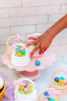 a child's hand reaching for an easter cake on a table with other decorations