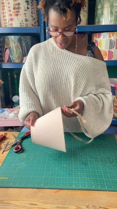 a woman is making something out of paper on a cutting board with scissors and pliers