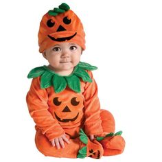 a baby sitting next to a pumpkin costume