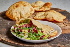 a salad and croissants are on a wooden board next to some bread