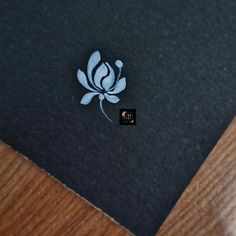 a close up of a black and white flower on a piece of paper next to a wooden table