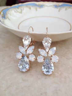 two pairs of earrings sitting on top of a table next to a white plate and bowl