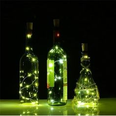 three bottles with lights in them sitting on a table