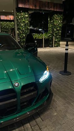 a green sports car parked in front of a building at night with its lights on