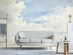 a white couch sitting in front of a painting on the wall next to a table