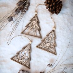 three metal ornaments with pine cones and twine on top of white furnishing