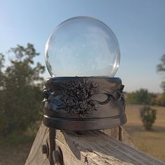 a glass ball sitting on top of a wooden rail