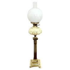 an old fashioned lamp with a white glass ball on it's top and gold base