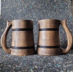 two wooden mugs sitting next to each other on top of a granite countertop